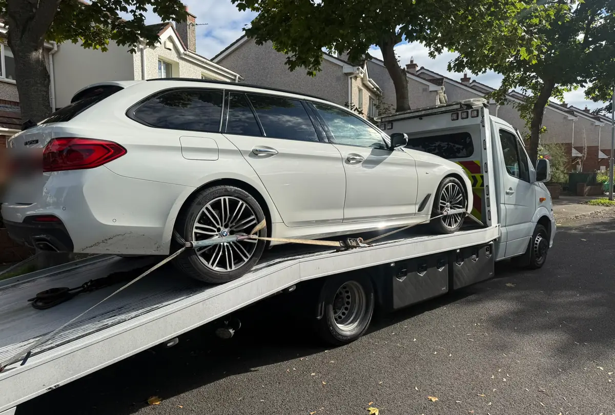 A white estate car strapped onto a car recovery flatbed with the ramp down on a Dublin street