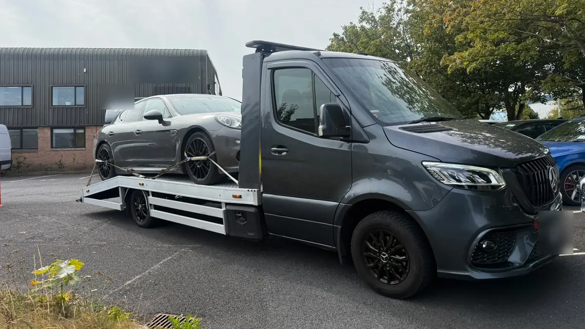 A grey sports saloon on a dark flatbed tow truck in a Dublin business park