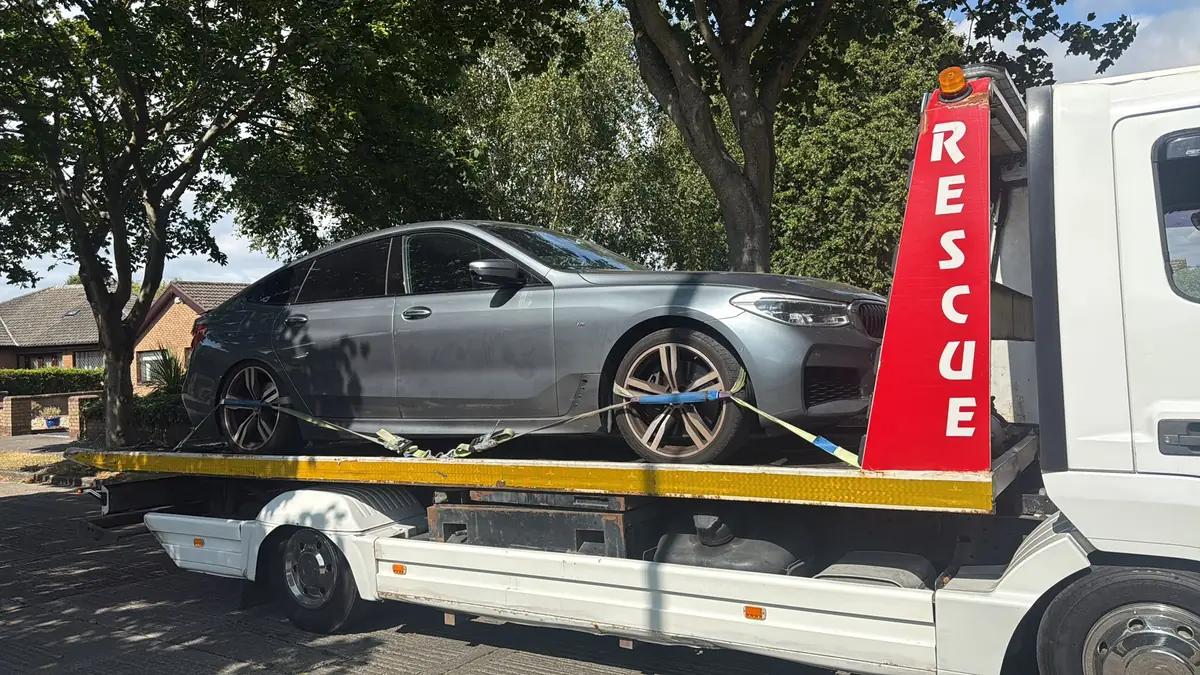 A grey saloon secured on the Recovery CC Atego flatbed beside the red RESCUE post, car recovery in Dublin