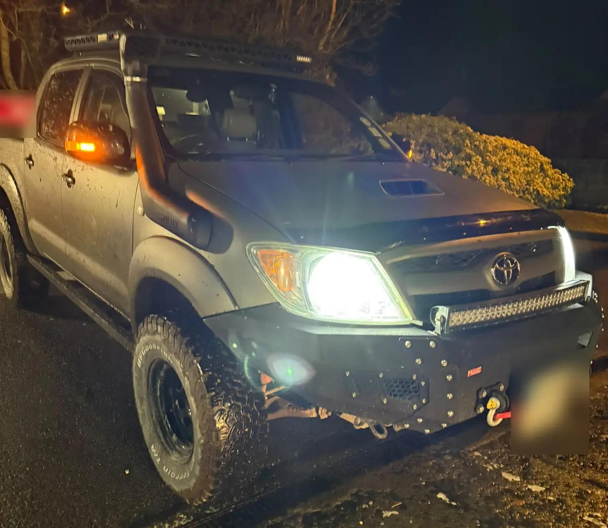 A 4x4 pickup sitting on a muddy verge at night, waiting for vehicle recovery near Dublin