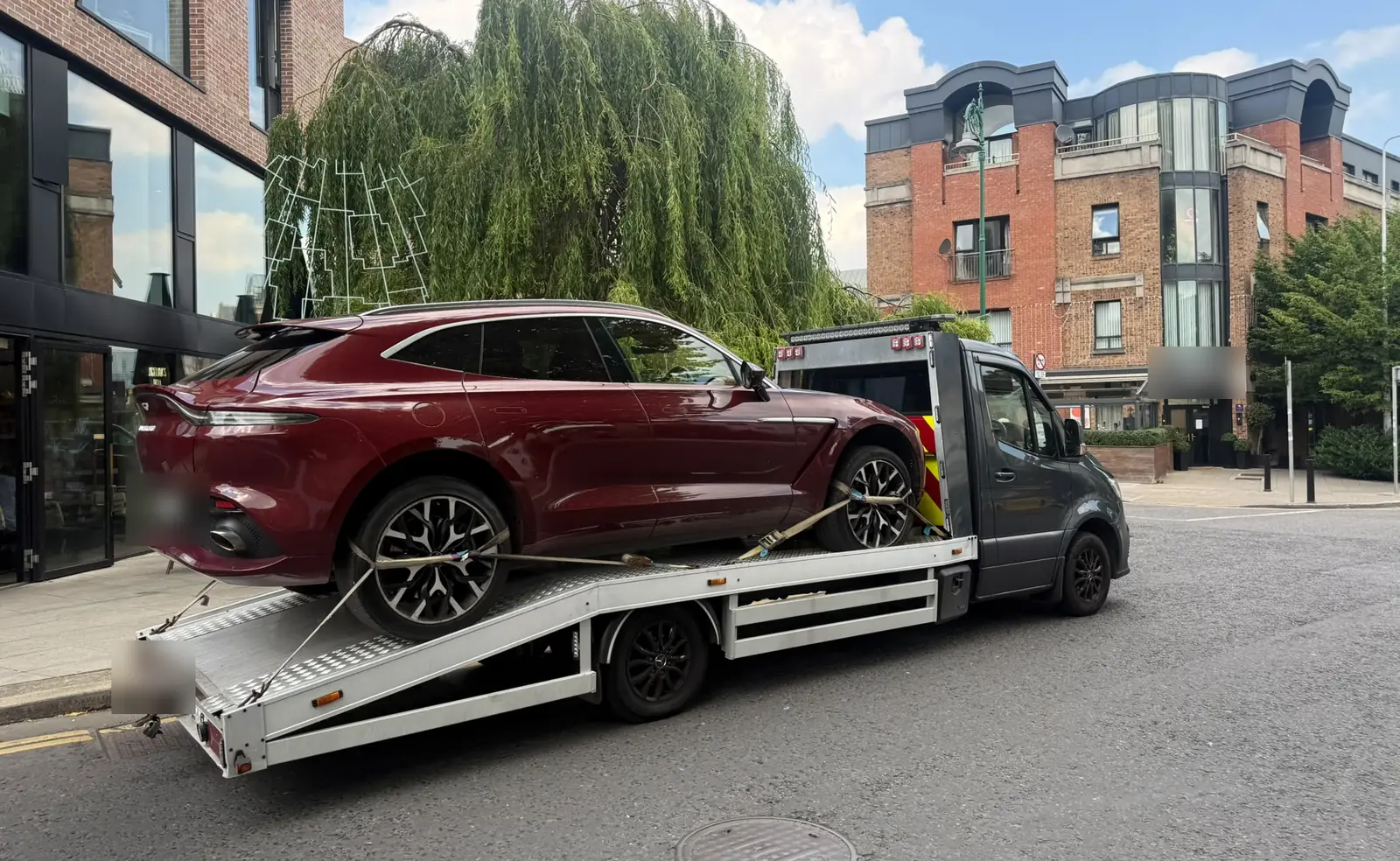 A luxury SUV on a flatbed tow truck on a Dublin city street, vehicle recovery
