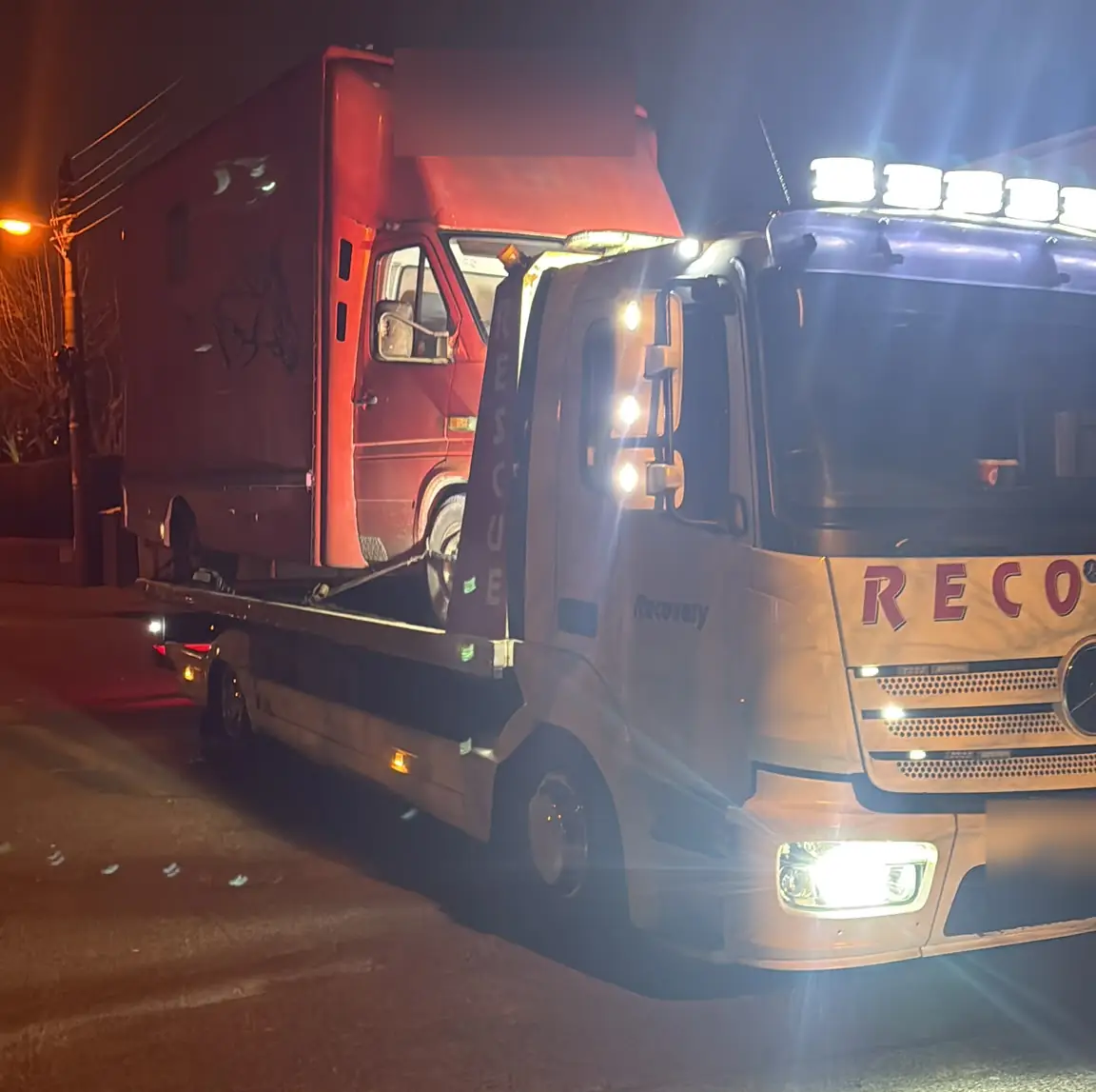A Recovery CC Mercedes Atego recovery truck with its work lights on at night